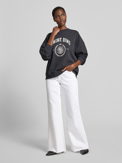 Frauenmodel trägt Flared Fit Jeans im 5-Pocket-Design von Anine Bing, weiß, mit Gürtelschlaufen, Knopf- und Reißverschluss, Ganzkörperansicht von vorne.
