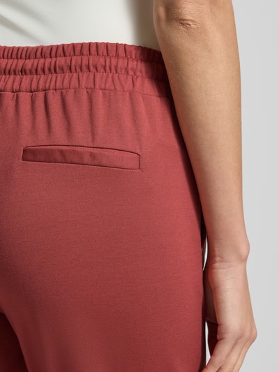 Frauenmodel trägt Stoffhose mit elastischem Bund Modell 'KATE' von ICHI, Viskose-Mix, Ziegelrot, Detailaufnahme Gesäßtasche, Nahaufnahme Oberschenkel.