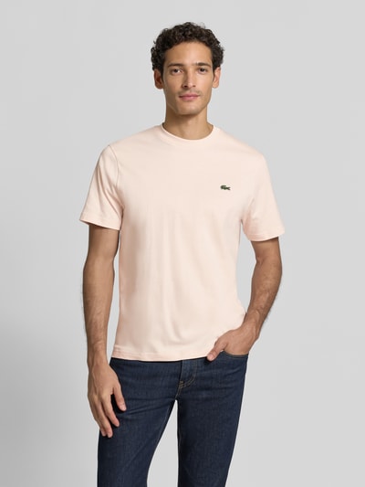 Männermodel trägt Regular Fit T-Shirt aus reiner Baumwolle von Lacoste in Hellrosa, glatte Textur, Ganzkörperansicht von vorne. Herren T-Shirt von Lacoste