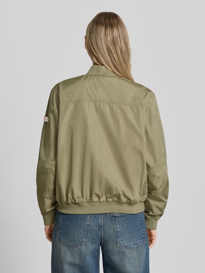 Frauenmodel trägt Bomberjacke mit Label-Patches Modell 'BROOKLYN NEO' von Frieda & Freddies, Olive, Gerader-Schnitt, Rückenlänge 49 cm, Ganzkörperansicht Rückansicht.
