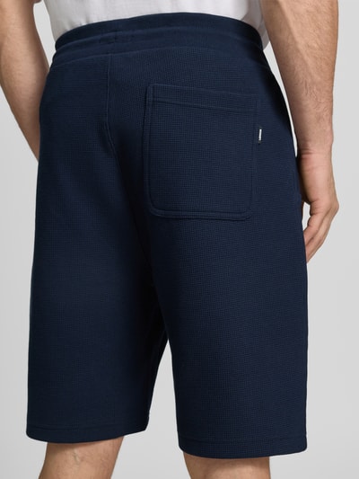 Männermodel trägt Shorts mit Strukturmuster und Tunnelzug von Lerros in Dunkelblau, Baumwoll-Mix mit Stretch-Anteil, Gesäßtasche, Regular-Fit, Ganzkörperansicht Rückansicht.