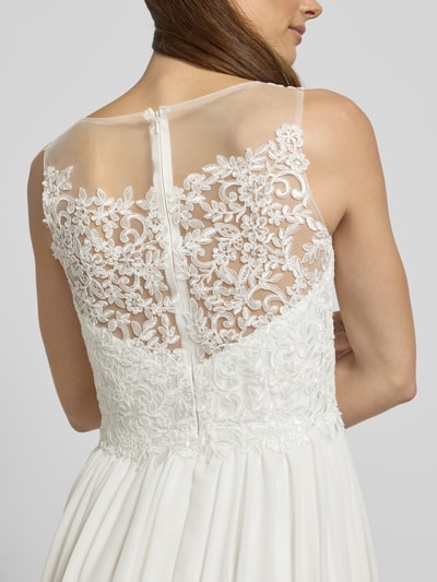 Kobieta nosi Brautkleid mit floraler Spitze od Mascara, biały kolor, kwiatowa koronka, półprzezroczysty materiał wierzchni, halka pod sukienkę, wszyty zamek błyskawiczny i haftka, taliowany krój, szerokie ramiączka, dekolt w kształcie serca, rozmiar 36: długość tyłu 107 cm, szerokość klatki piersiowej 40 cm, detailaufnahme pleców.