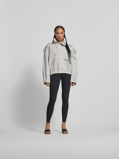 Frauenmodel trägt Jacke mit Stehkragen von black palms aus Baumwolle-Elasthan-Mix, Relaxed-Fit, Farbe Hellgrau, Ganzkörperansicht von vorne.