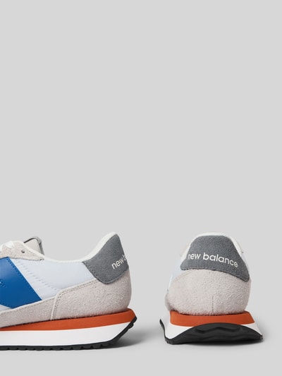 Produktfoto, Sneaker mit Logo-Detail von New Balance, szare i niebieskie elementy, pomarańczowa podeszwa, wiązanie, profilowana podeszwa, detal z logo, lekko matowa faktura, wysokość obcasa w rozmiarze 44: 4 cm, wysokość cholewki w rozmiarze 44: 8 cm, szerokość w rozmiarze 44: 6 cm.