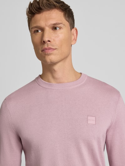 Männermodel draagt Regular Fit Pullover aus Baumwoll-Kaschmir-Mix Modell 'KANOVANO' van BOSS, effen lichtroze, label patch, Nahaufnahme Oberkörper.