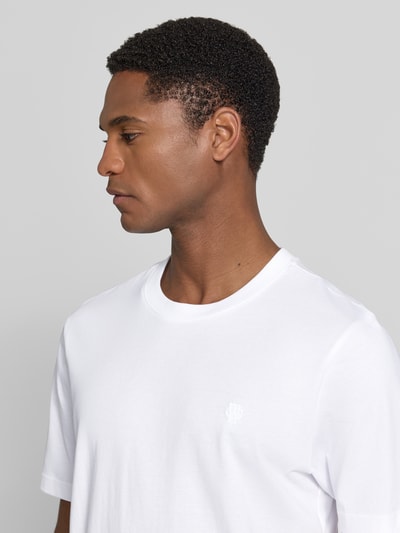 Mężczyznamodel nosi Regular Fit T-Shirt mit Logo-Stitching von MCNEAL, czysta bawełna, krój regular fit, okrągły dekolt, zbliżenie na górną część ciała.