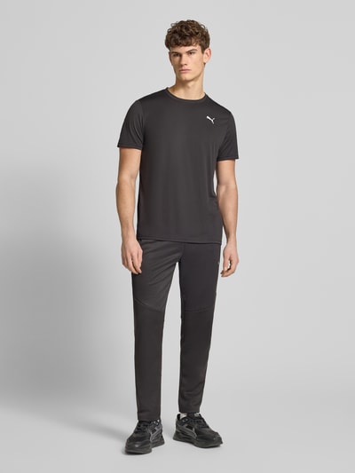 Męski model nosi T-Shirt z logo i okrągłym dekoltem od PUMA PERFORMANCE, regular fit, czarne, widok całej sylwetki z przodu.