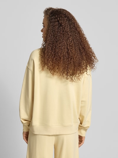 Frauenmodel trägt Sweatshirt mit Polokragen und Knopfleiste von Gina Tricot, Regular Fit, überschnittene Schultern, hellgelb, Ganzkörperansicht Rückansicht.