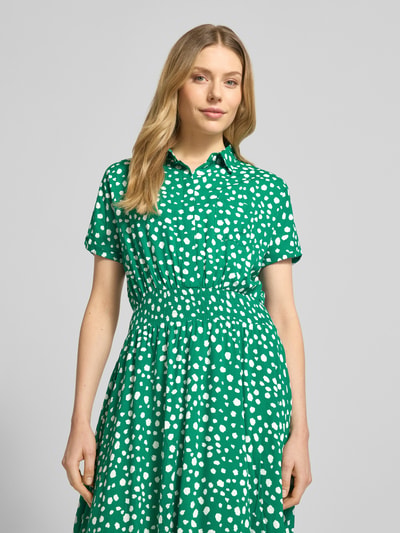 Frauenmodel trägt Hemdblusenkleid aus Viskose in asymmetrischem Look von Apricot, grün mit weißen Punkten, Taillierter Schnitt, Hemdblusenkragen, Midikleid, Elastisches Taillenband, Reine Viskose, Größe S: Rückenlänge 126 cm, Brustweite 41 cm, Ärmellänge 13 cm, Nahaufnahme Oberkörper.