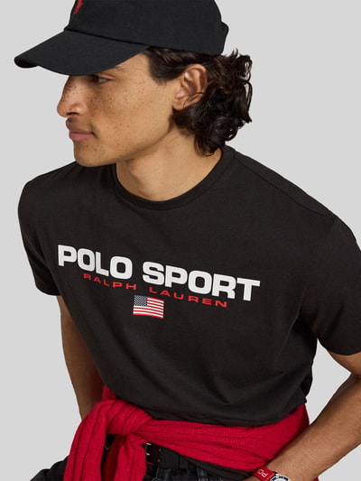 Męski model trägt Regular Fit T-Shirt aus reiner Baumwolle von Polo Ralph Lauren, czarne z białym nadrukiem, Ganzkörperansicht z przodu.