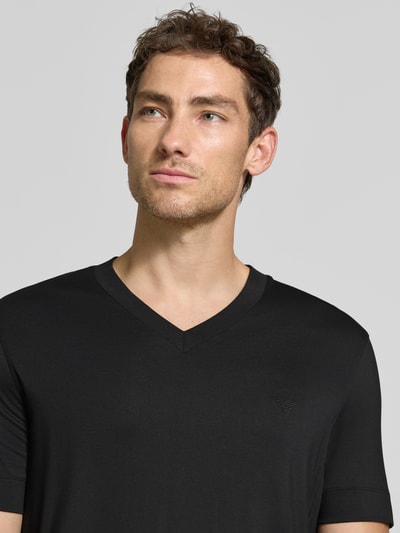 Männermodel trägt T-Shirt aus Modal-Mix mit V-Ausschnitt von Emporio Armani in Schwarz, Regular Fit, Label-Stitching, Nahaufnahme Oberkörper.