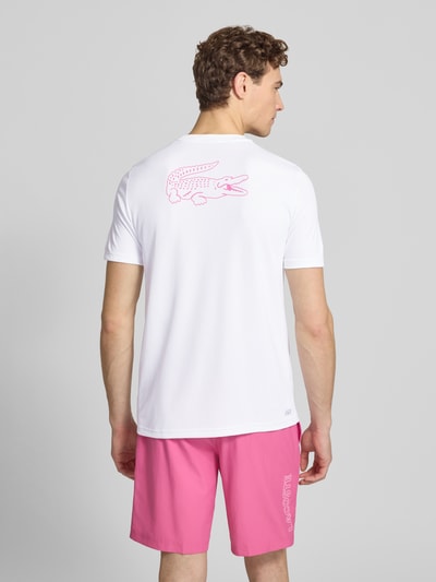 Männermodel trägt Regular Fit T-Shirt mit UV-Schutz 50+ von Lacoste Sport, weiß mit Logo-Patch und Logo-Print, Rückansicht Ganzkörperansicht.