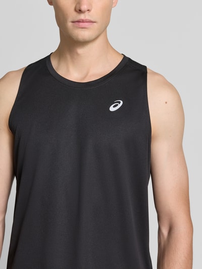Mężczyzna nosi top Regular Fit Top mit Logo-Print Model 'Core' von ASICS TIGER, czarny kolor, okrągły dekolt, nadruk z logo, Długość tyłu w rozmiarze M: 68 cm, Nahaufnahme górnej części ciała.
