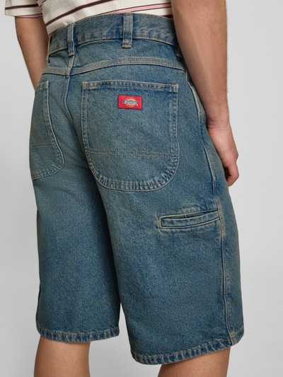 Mannenmodel draagt Loose Fit Bermudas met steekzakken van Dickies, denim, katoen, blauwe tinten, achteraanzicht detailopname.