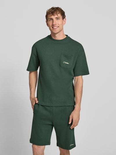 Männermodel trägt dunkelgrünes Herren T-Shirt mit Strukturmuster und Label-Stitching von PROHIBITED aus reiner Baumwolle, Regular-Fit, Rundhalsausschnitt, Brusttasche; Rückenlänge bei Größe M 64 cm; Ganzkörperansicht von vorne.