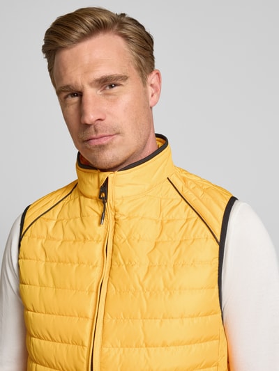 Männermodel trägt Regular Fit Weste in Stepp-Optik von NAUTGÅRD in Gelb mit Stehkragen, Nahaufnahme Oberkörper, strukturierte Textur.