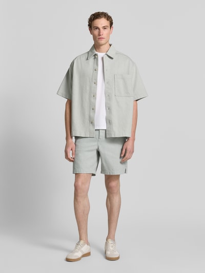 Männermodel trägt Regular Fit Shorts aus Baumwoll-Mix Modell 'SANDREW' von BOSS Orange, jednokolorowy, z naszywką z logo, szlufkami, zapięciem na guzik i ukrytym zamkiem błyskawicznym, kieszenią z tyłu, bocznymi wpuszczanymi kieszeniami, wykończenie: splot twill żakard, materiał: mieszanka bawełny, Ganzkörperansicht von vorne.