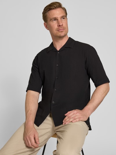 Mannelijk model draagt Regular Fit vrijetijdsoverhemd met structuurpatroon model 'Alfie' van DIGEL, elastische katoenmix, korte mouw, reverskraag, volledige knoopsluiting, kleur zwart, ruglengte 75 cm, schouderbreedte 50 cm, mouwlengte 31 cm, voorkant zichtbare knopen, textuur zichtbaar, voorkant bovenlichaam close-up.