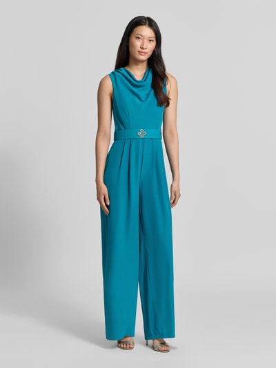 Frauenmodel trägt Jumpsuit mit Neckholder von Rinascimento in Türkis, Material-Mix mit Stretch, Stoffgürtel, taillierte Passform, Ganzkörperansicht von vorne.