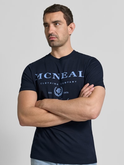 Mężczyznamodel nosi T-Shirt mit Label-Print und Rundhalsausschnitt von MCNEAL, męski t-shirt z nadrukiem z logo, bawełna, krój regular fit, długość tyłu w rozmiarze M: 68 cm, widok na górną część ciała z przodu.