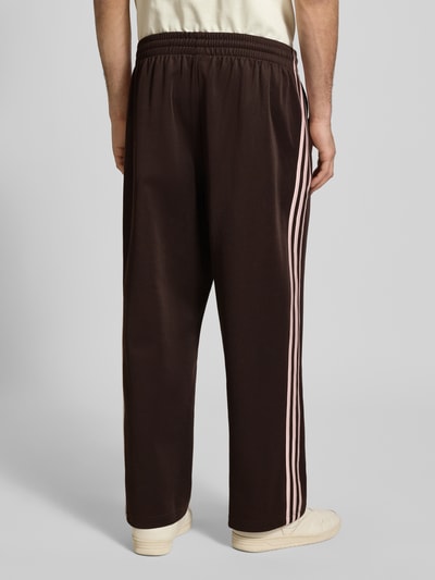 Männermodel trägt Straight Fit Sweatpants mit Logo-Stitching Modell 'Firebird' von adidas Originals, Baumwoll-Mix, Ziernaht, elastischer Bund, Ganzkörperansicht Rückansicht.