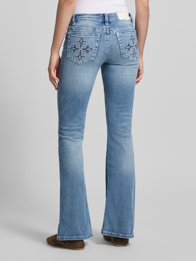 Frauenmodel trägt Flared Jeans im Used-Look Modell 'Poppy' von Gina Tricot aus Baumwoll-Mix mit Stretch-Anteil, 5-Pocket-Design, Knopf und Reißverschluss, hellblaue Waschung, sichtbare Nahtdetails, Bundweite bei Größe 36: 36 cm, Innenbeinlänge: 86 cm, Ganzkörperansicht Rückansicht.