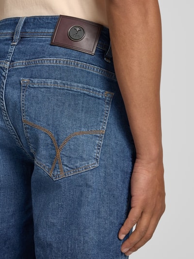 Männermodel trägt bermudy im 5 kieszeni Design Modell 'Fort' von JOOP! kolekcja, mieszanka bawełny z dodatkiem streczu, krój straight fit, zapięcie na guzik i zamek błyskawiczny, szerokość w rozmiarze 32: 48 cm, długość wewnętrzna nogawki w rozmiarze 32: 25 cm, niebieski denim, detal: naszywka z logo, detal: kontrastowe przeszycia, detailaufnahme