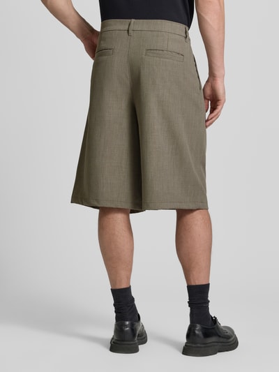 Männermodel trägt Bermudas mit Gesäßtaschen Modell 'Bin Guan' von WOODBIRD in Oliv mit geradem Schnitt, Material-Mix, Ganzkörperansicht Rückansicht.