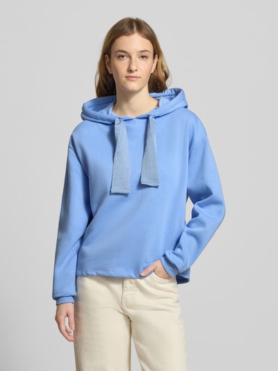 Modelka kobieta nosi Regular Fit Hoodie aus Baumwoll-Mix Modell 'CHILLI' od Pieces, niebieski, gładki, długi rękaw, kaptur ze sznurkiem, label stitching, materiał sweat, krój regular fit, zdjęcie całej sylwetki z przodu.