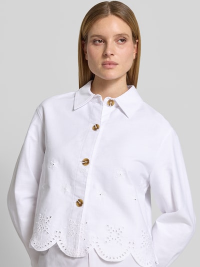 Frauenmodel trägt Jacke mit Lochstickerei Modell 'Marietta' von GUIDO MARIA KRETSCHMER WOMAN in Weiß, gerader Schnitt, Hemdblusenkragen, Knopfleiste, reine Baumwolle, strukturierte Oberfläche, Nahaufnahme Oberkörper.