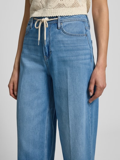 Frauenmodel trägt Wide Leg Culotte-Jeans aus Lyocell-Baumwoll-Mix Modell 'SURI' von s.Oliver RED LABEL in hellem Denim, Tunnelzug und 5-Pocket-Design, Nahaufnahme Oberkörper.