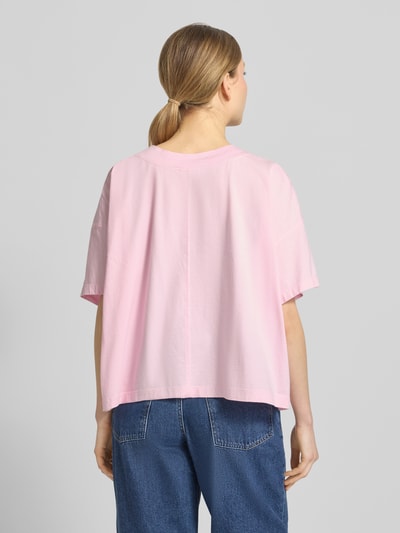 Frauenmodel trägt T-Shirt mit überschnittenen Schultern Modell 'GIXY' von American Vintage in Hellrosa, lockere Passform, Rückansicht, Ganzkörperansicht Rückansicht.