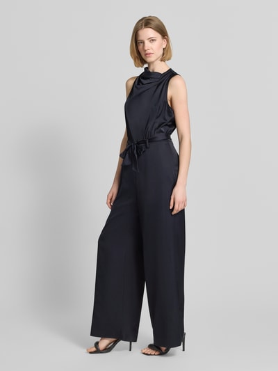 Frauenmodel trägt Jumpsuit aus Satin im ärmellosen Design von comma in Dunkelblau, taillierte Passform, Stoffband, Ganzkörperansicht von vorne.