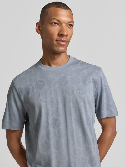 Männermodel trägt Regular Fit T-Shirt aus reiner Baumwolle von BOSS, hellgrau mit dezentem Muster, Kontext: BOSS Green, Nahaufnahme Oberkörper.