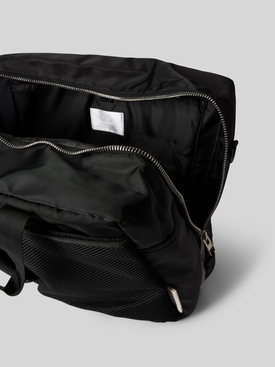 Produktfoto, schwarze Tasche mit Logo-Detail von AY STUDIOS, Reißverschluss, Netztaschen, verstellbarer Schulterriemen, Innenfach sichtbar
