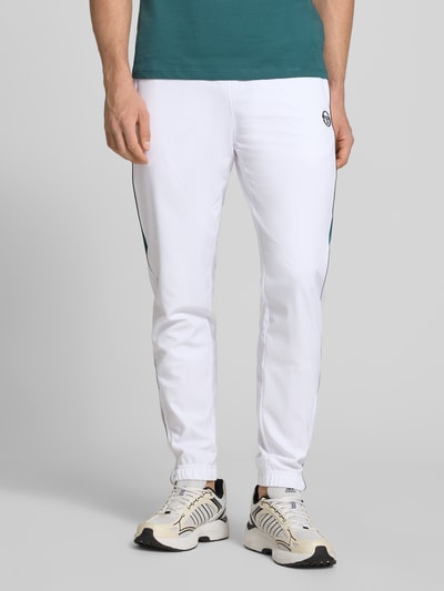 Männermodel trägt sweatpants met logostitching model 'CASPIO' van SERGIO TACCHINI in wit met elastische band, trekkoord en zij-steekzakken, materiaalmix met stretch, nauwsluitend model, binnenbeenlengte bij maat M 78 cm, detailopname voorkant.