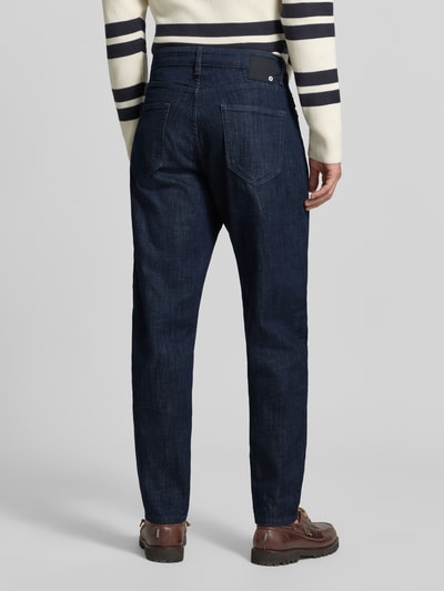 Männermodel trägt Relaxed Fit Jeans aus Baumwoll-Mix Modell 'Tan' von Strellson in Dunkelblau, Struktur leicht grob, Ganzkörperansicht Rückansicht, Herren Relaxed Fit Jeans von Strellson.