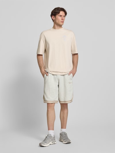 Mężczyznamodel nosi męski t-shirt z bawełny w kroju oversized fit Pegador Oversized T-Shirt mit rückseitigem Print Modell 'Pedroche', z nadrukiem z tyłu, okrągłym dekoltem, beżowy, długość tyłu w rozmiarze M: 71 cm, Ganzkörperansicht von vorne.