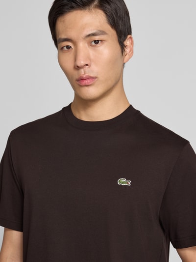 Męski model nosi Regular Fit T-Shirt aus reiner Baumwolle od Lacoste, efekt: jednolity kolor, haftowane logo, okrągły dekolt, krótki rękaw, bawełna; zbliżenie na górę.