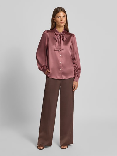 Vrouwenmodel draagt Regular Fit Hemdbluse aus Satin van Christian Berg Woman Selection, satijn, bruinroze tinten, sierstrik, lange mouwen, hemdkraag, gladde textuur, vooraanzicht volledig lichaam.