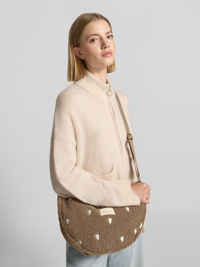 Vrouwenmodel draagt Shoulder Bag mit Logo-Patch van Studio Noos in beige met all-over motiefstitching, verstelbare schouderband, hoofdvak met ritssluiting, logopatch, breedte 40 cm, lengte 22 cm, diepte 15 cm, bandlengte 65 cm, ganzekopaanzicht van voren.