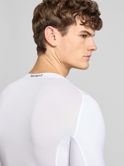 Männermodel trägt Longsleeve mit Label-Print von adidas Training, weißer Material-Mix mit Stretch, Rückenansicht, Nahaufnahme Oberkörper.