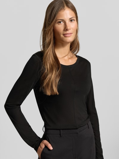 Frauenmodel trägt Longsleeve in semi-transparenter Optik von MYON, taillierter Schnitt, Rundhalsausschnitt, Ziernaht, Nahaufnahme Oberkörper.