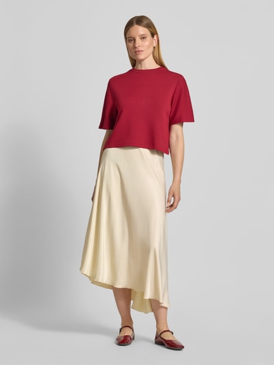 Kobieta modelka nosi spódnicę midi z mieszanki wiskozy w asymetrycznym kroju, model 'Bethanie' od MSCH Copenhagen, elastyczny pas, szerokość w rozmiarze S: 39 cm, całkowita długość w rozmiarze S: 72 cm, ujęcie całej sylwetki od przodu.