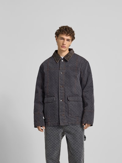 Männermodel trägt Jacke mit echtem Rindsleder-Besatz von DAILY PAPER, reine Baumwolle, Umlegekragen, relaxed Fit, Ganzkörperansicht von vorne.