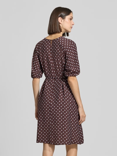 Frauenmodel trägt Knielanges Kleid aus Viskose-Mix von zero, braun mit kreisförmigem Muster, taillierte Passform, Ganzkörperansicht Rückansicht.