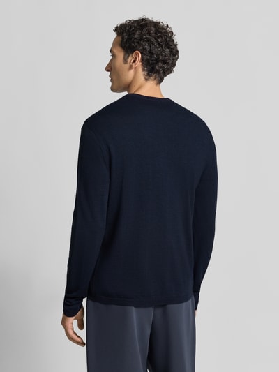 Männermodel trägt Strickpullover mit Henley-Kragen von DRYKORN in Dunkelblau, reine Baumwolle, gerader Schnitt, Ganzkörperansicht Rückansicht.