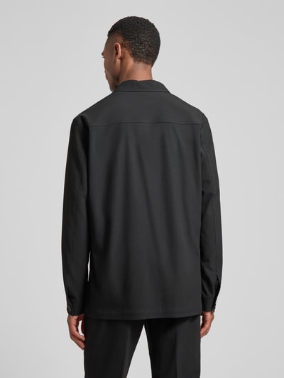 Männermodel trägt schwarzes Relaxed Fit Hemdjacke mit Viskose-Anteil Modell 'Bill' von DIGEL, strukturierte Oberfläche, Ganzkörperansicht Rückansicht. Herren Hemdjacke mit Reverskragen und aufgesetzten Taschen, elastischer Material-Mix, Rückenlänge 75 cm bei Größe 50.