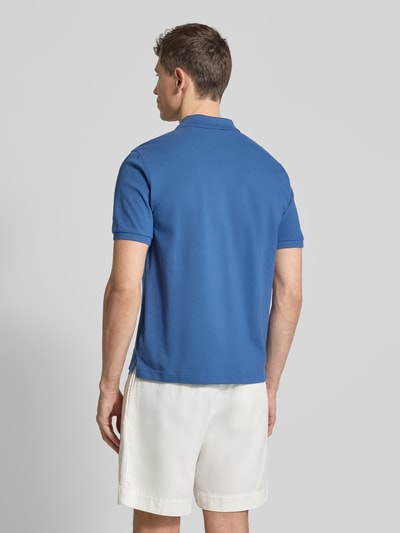 Männermodel trägt Slim Fit Poloshirt mit Logo-Stitching van Gant in blauw, puur katoen, polokraag, korte mouw, ruglengte 70 cm, ganzkörperansicht Rückansicht.