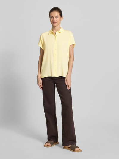 Frauenmodel trägt Regular Fit Bluse aus Viskose von Christian Berg Woman in zartem Gelb mit Hemdblusenkragen und Knopfleiste, Ganzkörperansicht von vorne. Rückenlänge bei Größe 36: 64 cm, Ärmellänge: 15 cm, Damen Bluse.